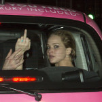 Jennifer Lawrence Flicks The Bird With ‘Love Is All You Need’ Printed Above Her Head Riding A Pink Taxi With Nicholas Hoult